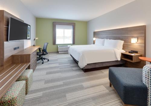 a hotel room with a bed and a flat screen tv at Holiday Inn Express & Suites - Plano - The Colony by IHG in The Colony
