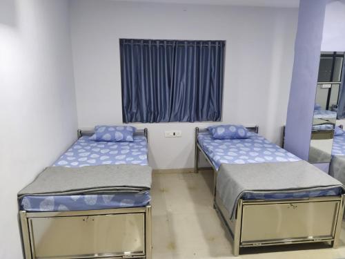 two beds in a room with a window at Shiv Sai Dormitory in Vadodara