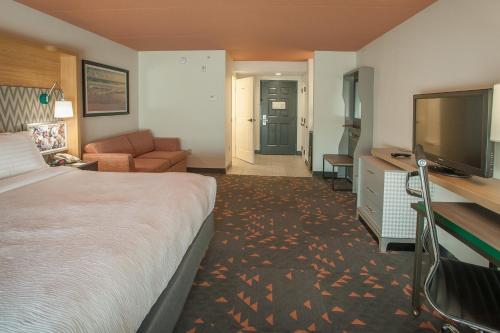 a hotel room with a bed and a flat screen tv at Holiday Inn Pensacola - University Area by IHG in Pensacola