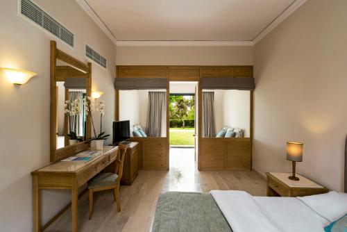 a bedroom with a bed and a desk and a mirror at Mitsis Rodos Maris in Kiotari