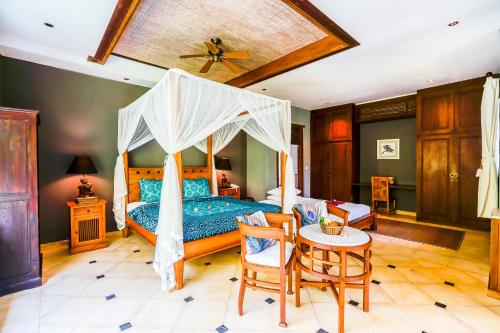 um quarto com uma cama de dossel com uma mesa e cadeiras em Villa Beji Indah em Ubud
