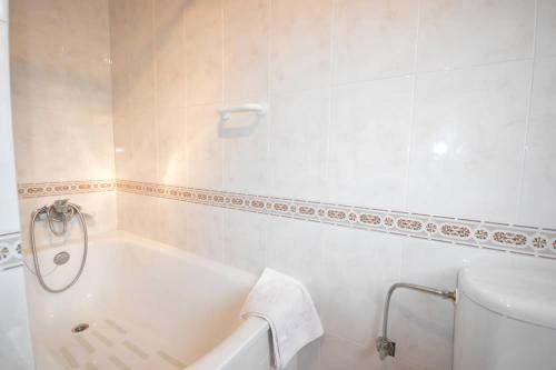 a white bathroom with a tub and a toilet at Apartamentos La Huertina in Canales