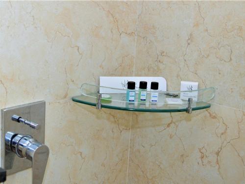 a glass shelf on a wall with cosmetics on it at Hotel Siddhartha Inn in Udaipur
