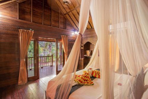 1 dormitorio con cama con dosel en una casa en The Well House, en Nusa Lembongan