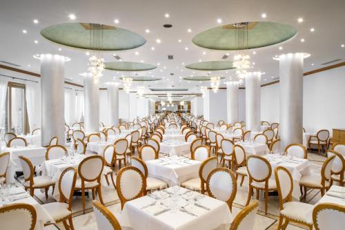 a banquet hall with white tables and chairs and chandeliers at Mitsis Rodos Maris in Kiotari