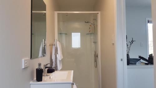a bathroom with a sink and a shower with a mirror at Lodges on Pearson - Unit 2 in Cromwell