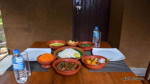 a table with bowls of food and bottles of water at Gal Oruwa Resort in Dambulla