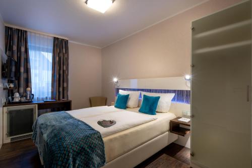 a hotel room with a large bed with blue pillows at Hotel Stadt Heidelberg in Darmstadt