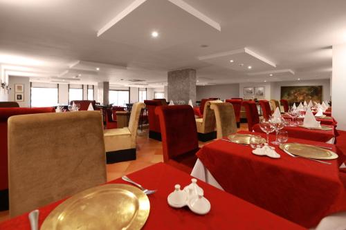 a dining room with red tables and chairs and tablesearcher at Kenzi Rose Garden in Marrakech