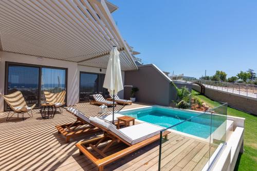 a deck with a swimming pool and chairs and an umbrella at Onira Suite Dreams in Hersonissos