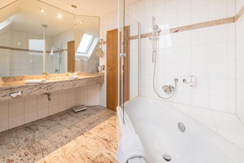 a bathroom with a tub and a shower and a sink at Göbels Hotel zum Löwen in Friedewald