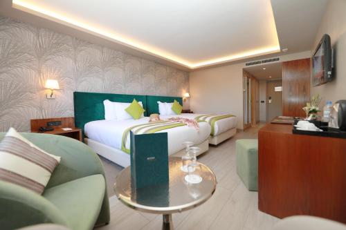 a hotel room with two beds and a couch at Kenzi Rose Garden in Marrakech