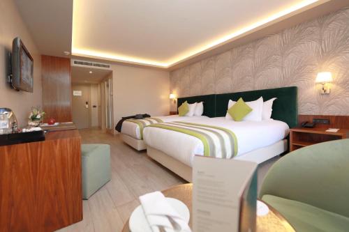 a hotel room with a large bed and a desk at Kenzi Rose Garden in Marrakech