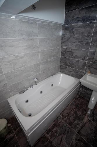 a white bath tub in a bathroom with a sink at Hotel Shpija e Gjyshit in Shkodër