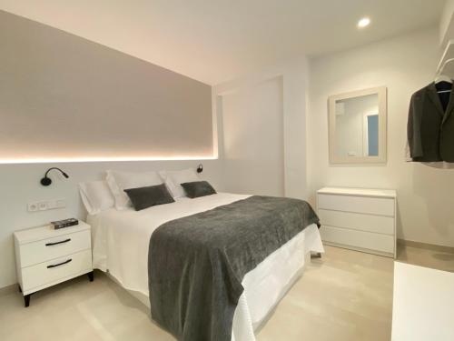 a white bedroom with a white bed and a mirror at HNN GRANADA in Granada