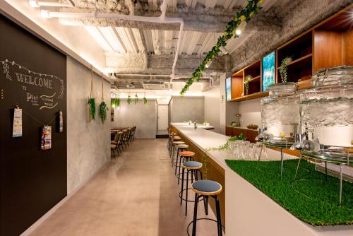 a restaurant with a bar with stools and green grass at plat hostel keikyu minowa forest in Tokyo