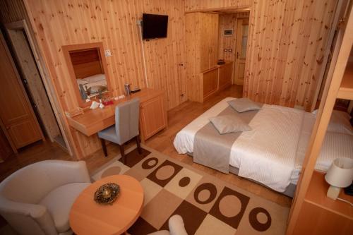 a bedroom with a bed and a desk and a sink at Hotel Shpija e Gjyshit in Shkodër