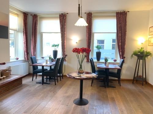 a dining room with tables and chairs and windows at Hotel het Gemeentehuis Uithuizen in Uithuizen