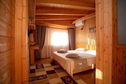 a bedroom with a bed in a room with wooden walls at Hotel Shpija e Gjyshit in Shkodër