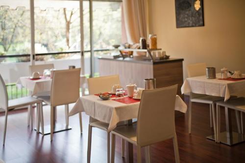 un restaurante con mesas y sillas blancas y una ventana en Botton D'Oro 2 Rozzano en Basiglio