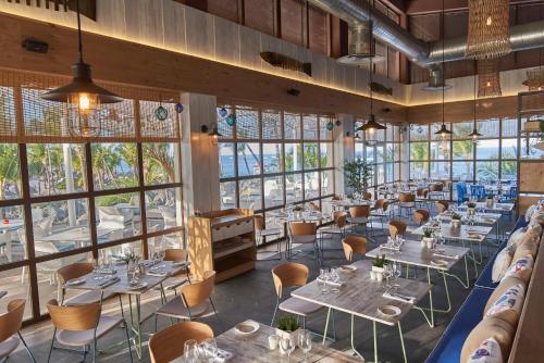 a dining room with tables and chairs and windows at Bahia Principe Luxury Ambar - Adults Only All Inclusive in Punta Cana