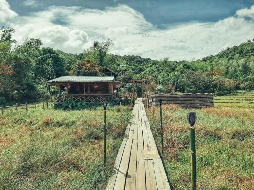 a wooden walkway leading to a building in a field at Cabanas de Nacpan Camping Resort in El Nido