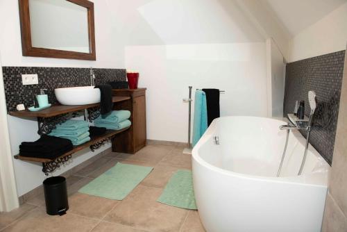 La salle de bains est pourvue d'une baignoire blanche et d'un lavabo. dans l'établissement StudioBeerse met Sauna Zwembad en Spa, à Beerse