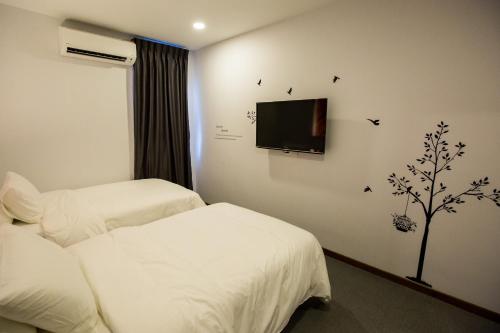 a hotel room with two beds and a tv on the wall at RS Boutique Hotel in Kluang