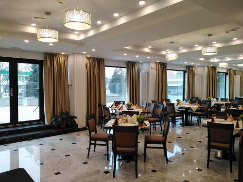 a dining room with tables and chairs and windows at Hotel Sarmis in Deva