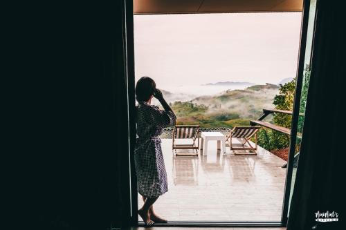 a woman standing outside a door looking at a view at Papa Garden Khaokho in Khao Kho