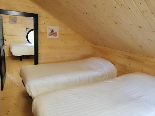 a room with two beds in a wooden cabin at Les Chalets de Grazimis in Condom