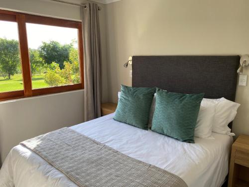 een slaapkamer met een bed met groene kussens en een raam bij Viettz Suite Annex in Stellenbosch