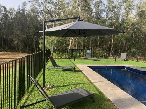 an umbrella and chairs next to a pool at The Woods Pokolbin in Pokolbin