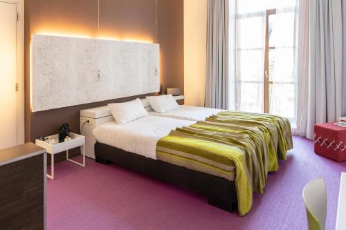 a bedroom with a large bed and a large window at Eburon Hotel in Tongeren