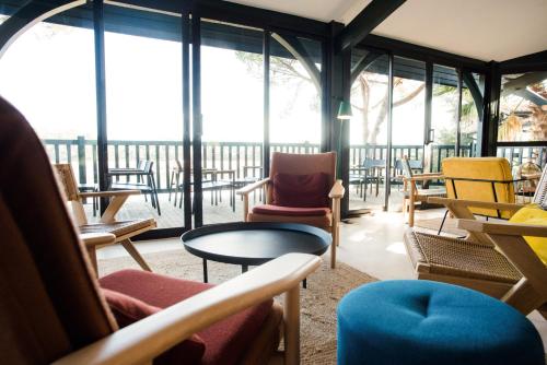 a room with chairs and tables and windows at Hôtel Les Hortensias du Lac in Hossegor