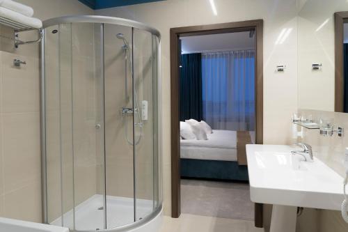 a bathroom with a shower and a sink and a bed at Hotel Moran & SPA in Powidz