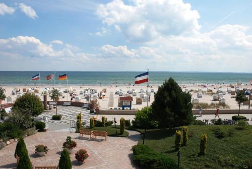 a view of a beach with flags and the ocean at Hotel Strandidyll in Grömitz