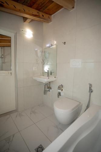 a white bathroom with a tub and a sink at Hotel Grandpa's House in Shkodër