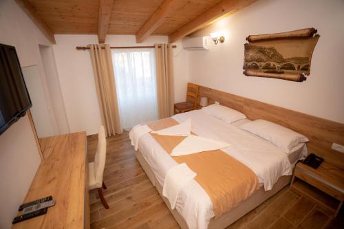 a bedroom with a bed and a table and a television at Hotel Grandpa's House in Shkodër