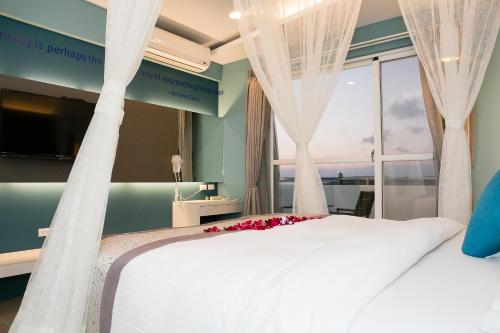 a bedroom with a large white bed with a window at Bai Sha Tan Cottage in Kenting