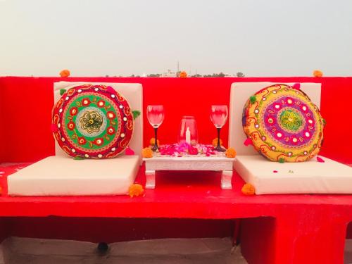 a red table with two plates and wine glasses at Oolala - Your lake house in the center of Udaipur in Udaipur