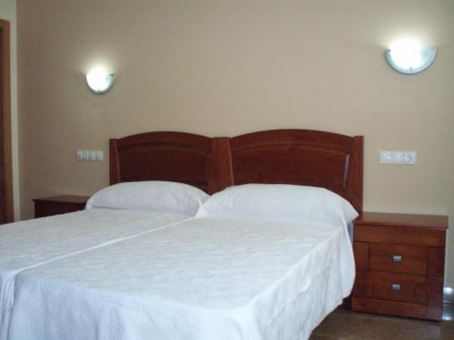 1 dormitorio con 1 cama grande con sábanas blancas en Hostal el Altozano, en Montánchez