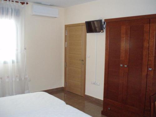 1 dormitorio con 1 cama y armario de madera en Hostal el Altozano, en Montánchez