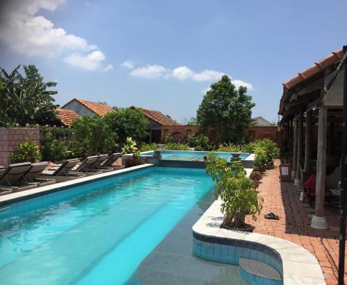 a swimming pool with lounge chairs in a resort at Phong Nha Farmstay in Phong Nha