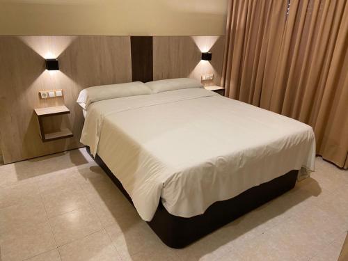 1 dormitorio con 1 cama blanca grande y 2 lámparas en Hotel La Parada, en Ontígola