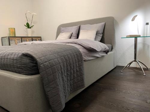 a bedroom with a bed with a gray comforter and a table at Central & Elegant Room in Biel in Biel