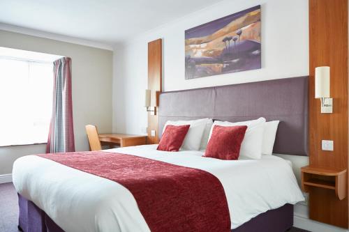 a hotel room with a large bed with red pillows at Wheatsheaf by Chef & Brewer Collection in North Waltham