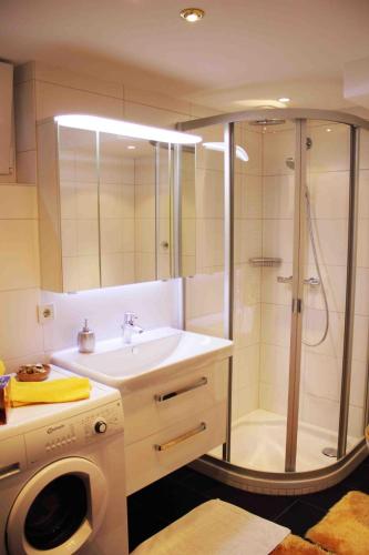 a bathroom with a shower and a sink and a washing machine at Ferienwohnung Schauberger in Oberammergau