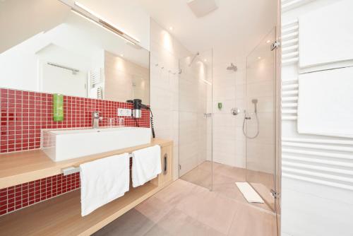 La salle de bains est pourvue d'un lavabo et d'une douche. dans l'établissement Hotel VICTORIA Nürnberg, à Nuremberg