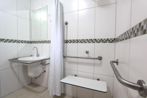 une salle de bain blanche avec un lavabo et une douche dans l'établissement Pousada das Cavernas, à Iporanga